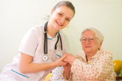 a nurse holding the hand of an old woman