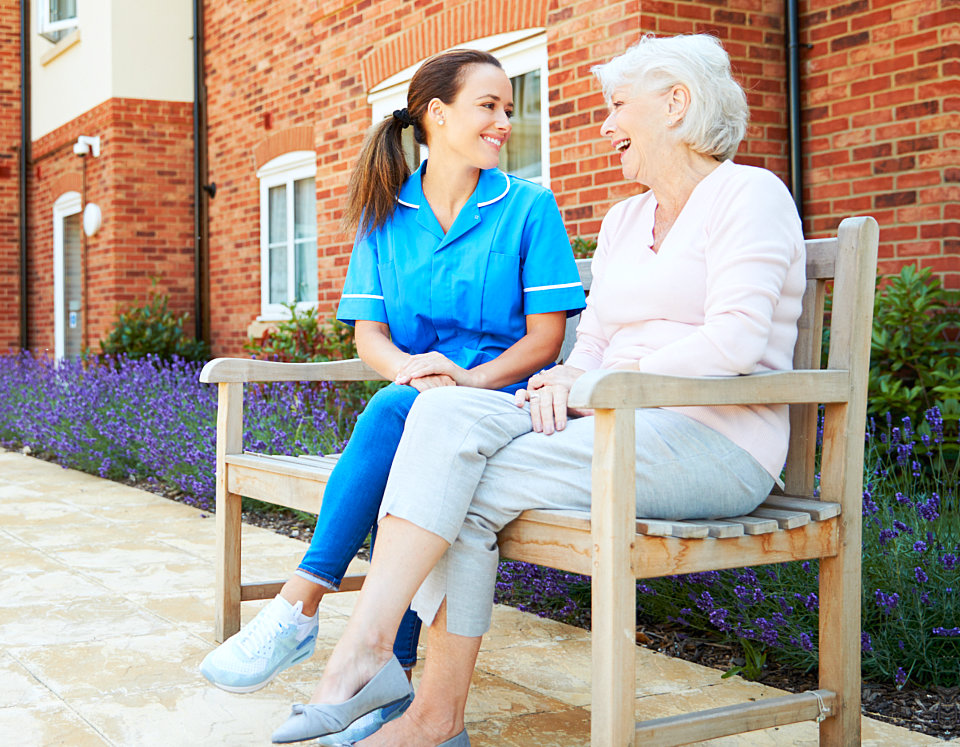 Caregiver talking with an elderly woman outdoors